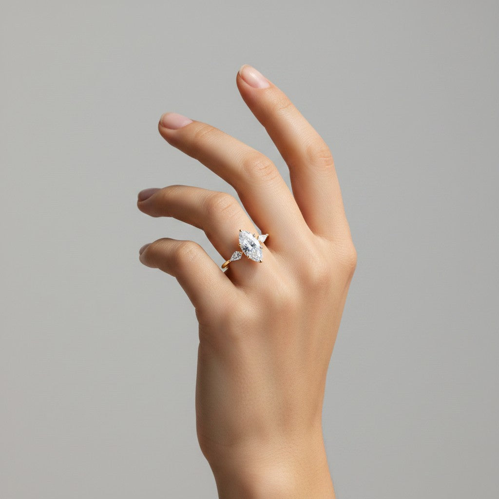 My Store 4 18K solid gold trilogy ring featuring a marquise-cut lab-grown diamond on a hand against a grey background.