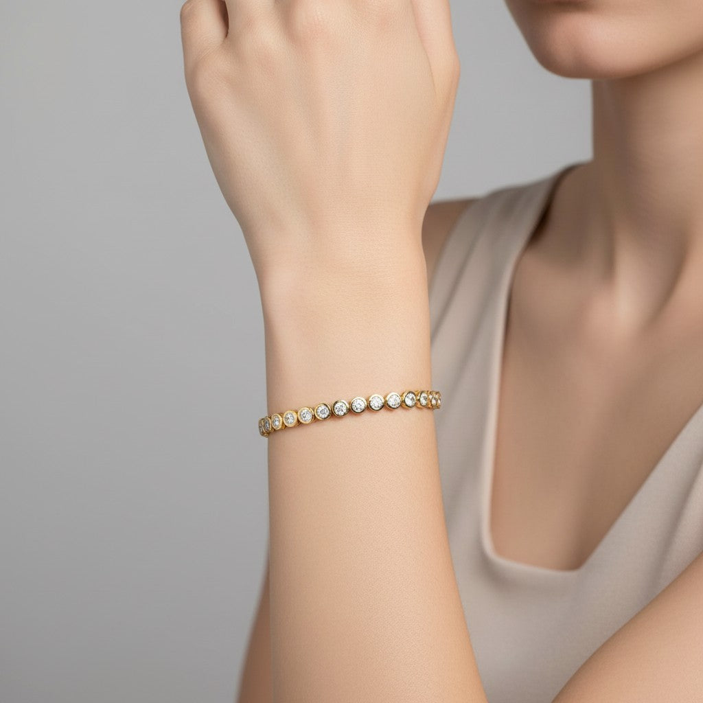 My Store 4 modern bezel diamond tennis bracelet in yellow gold worn on a woman's wrist.
