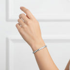 My Store 4 bezel set round diamond tennis bracelet in white gold worn on a woman's wrist against a white background
