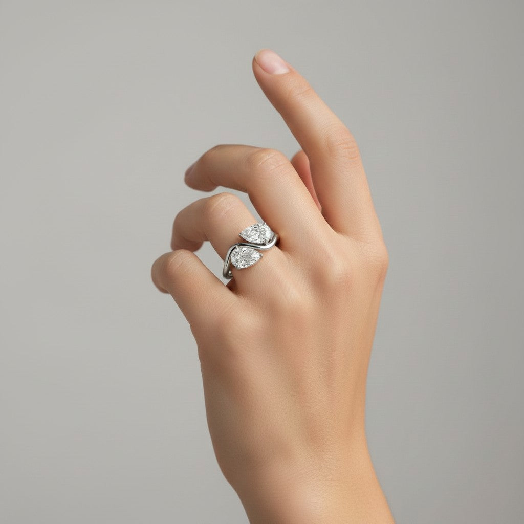 My Store 4 bypass engagement ring with two pear-cut diamonds on a fluid S-curve white gold band worn on a finger