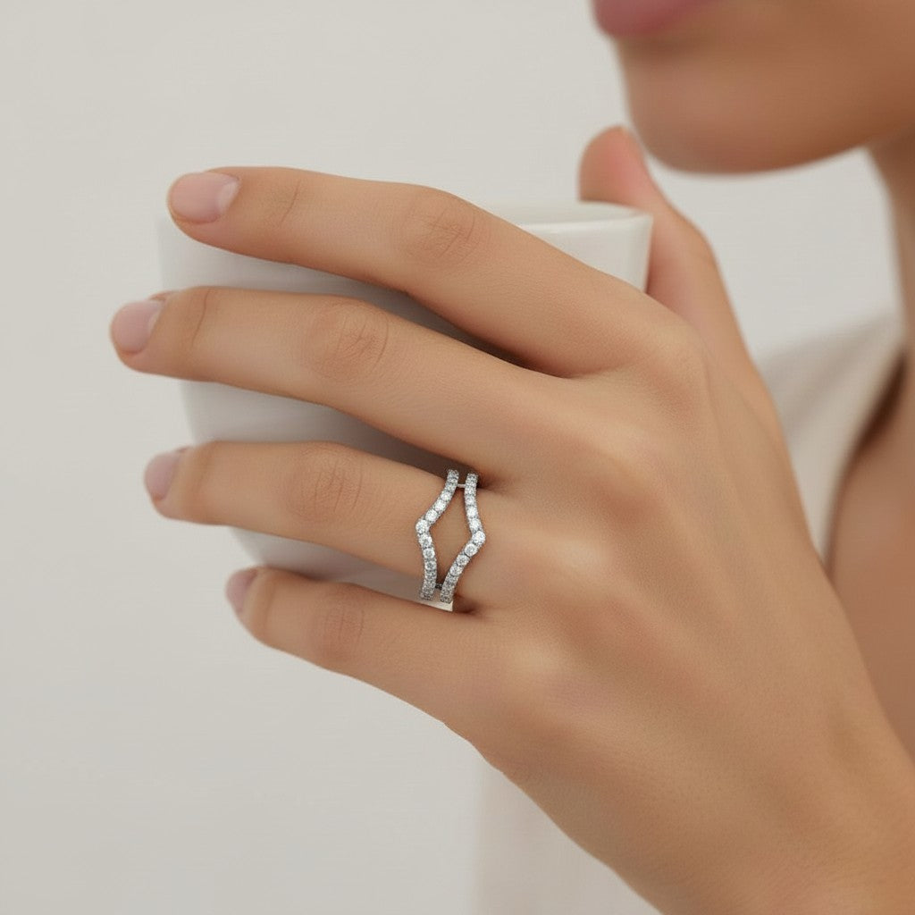 My Store 4 double chevron ring enhancer in white gold with micro-pavé diamonds worn on a finger while holding a cup.