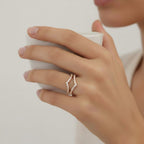 My Store 4 double chevron pavé diamond ring enhancer in yellow gold worn on a finger while holding a white cup.