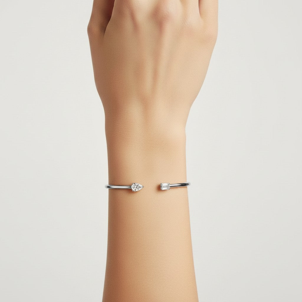 My Store 4 open cuff bracelet featuring a pear-cut and emerald-cut diamond on a sleek white gold band on a wrist.