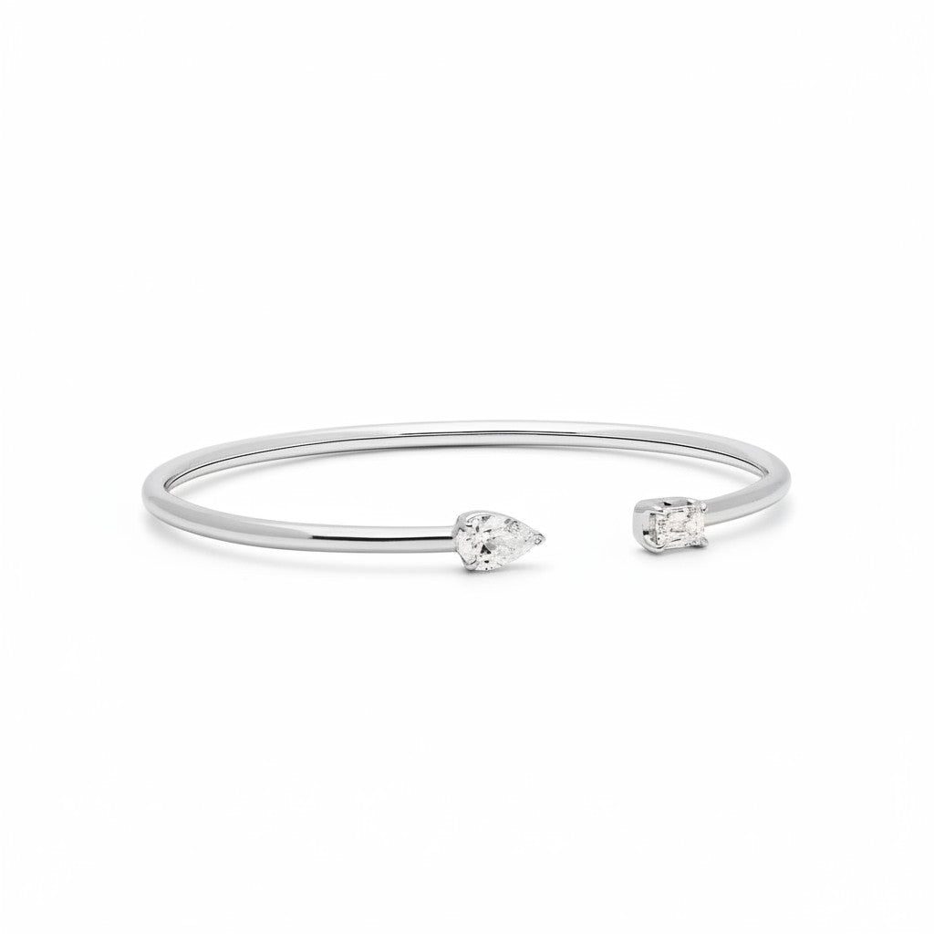 My Store 4 open cuff bracelet in white gold with a pear-cut diamond on one end and an emerald-cut diamond on the other.