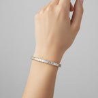 My Store 4 custom emerald cut diamond tennis bracelet in yellow gold worn on a woman's wrist.