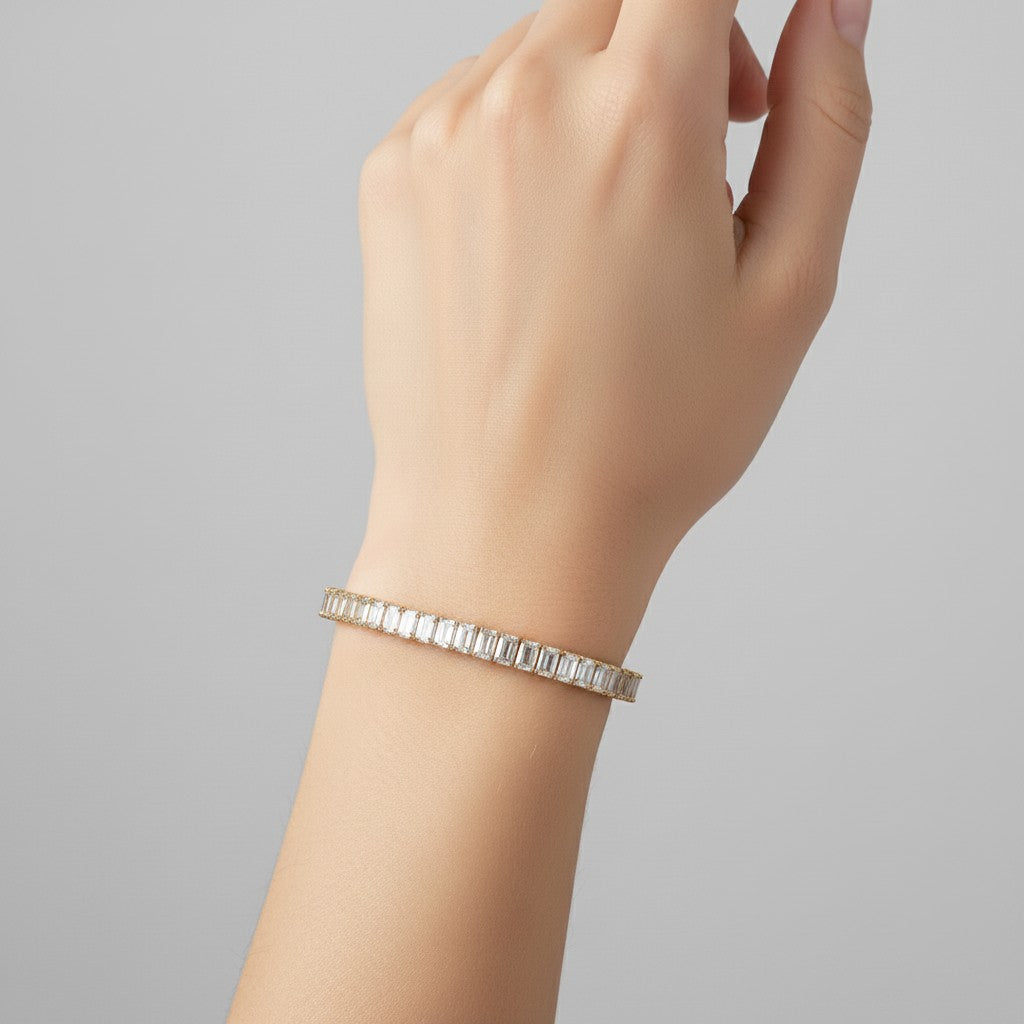 My Store 4 custom emerald cut diamond tennis bracelet in yellow gold worn on a woman's wrist.