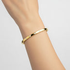 My Store 4 yellow gold bangle bracelet with flush set round diamonds worn on a wrist
