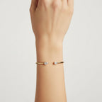 My Store 4 open cuff bracelet in yellow gold featuring an asymmetrical pear-cut and emerald-cut diamond on a wrist.