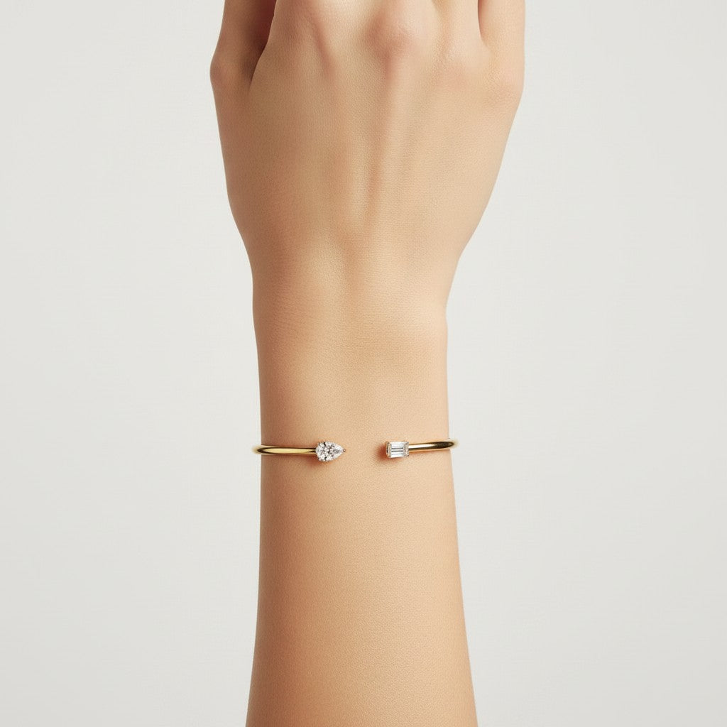 My Store 4 open cuff bracelet in yellow gold featuring an asymmetrical pear-cut and emerald-cut diamond on a wrist.