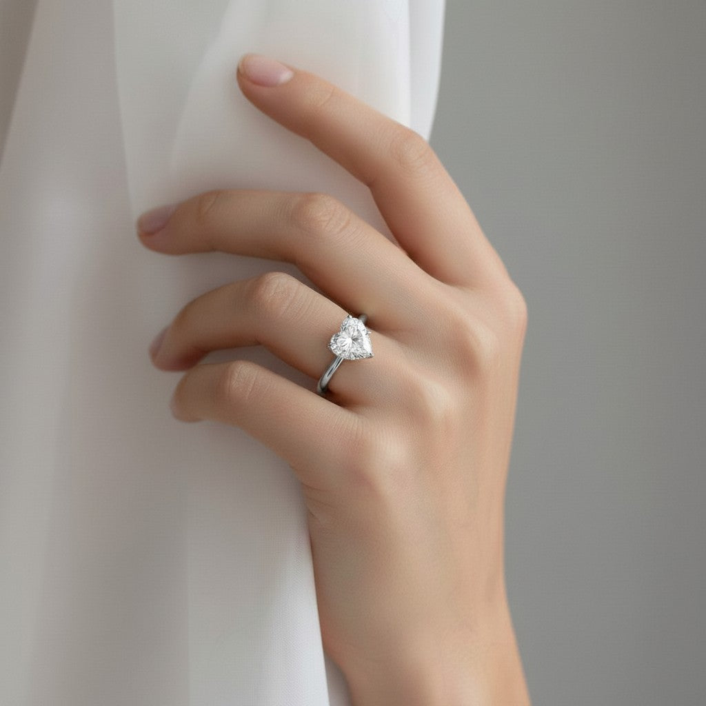 My Store 4 18K solid gold solitaire diamond ring with a heart-shaped stone worn on a woman's hand against fabric.