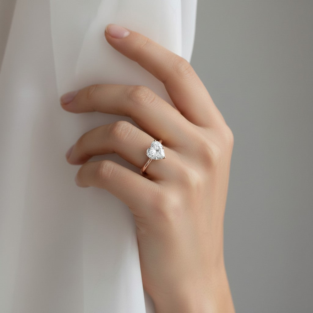 My Store 4 18K solid gold solitaire heart-shaped diamond ring worn on a woman's finger against a white fabric backdrop.