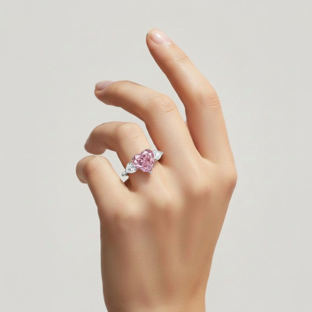 My Store 4 18K solid gold trilogy ring featuring a heart-cut fancy pink lab-grown diamond on a woman's finger.