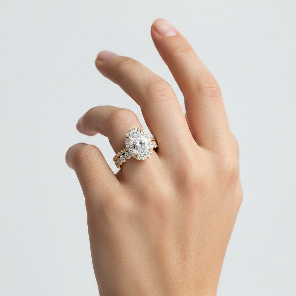 My Store 4 oval diamond halo engagement ring and matching eternity wedding band set in 18k yellow gold on a hand.