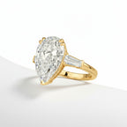 My Store 4 pear cut engagement ring with tapered baguette side diamonds in polished yellow gold on a white surface.