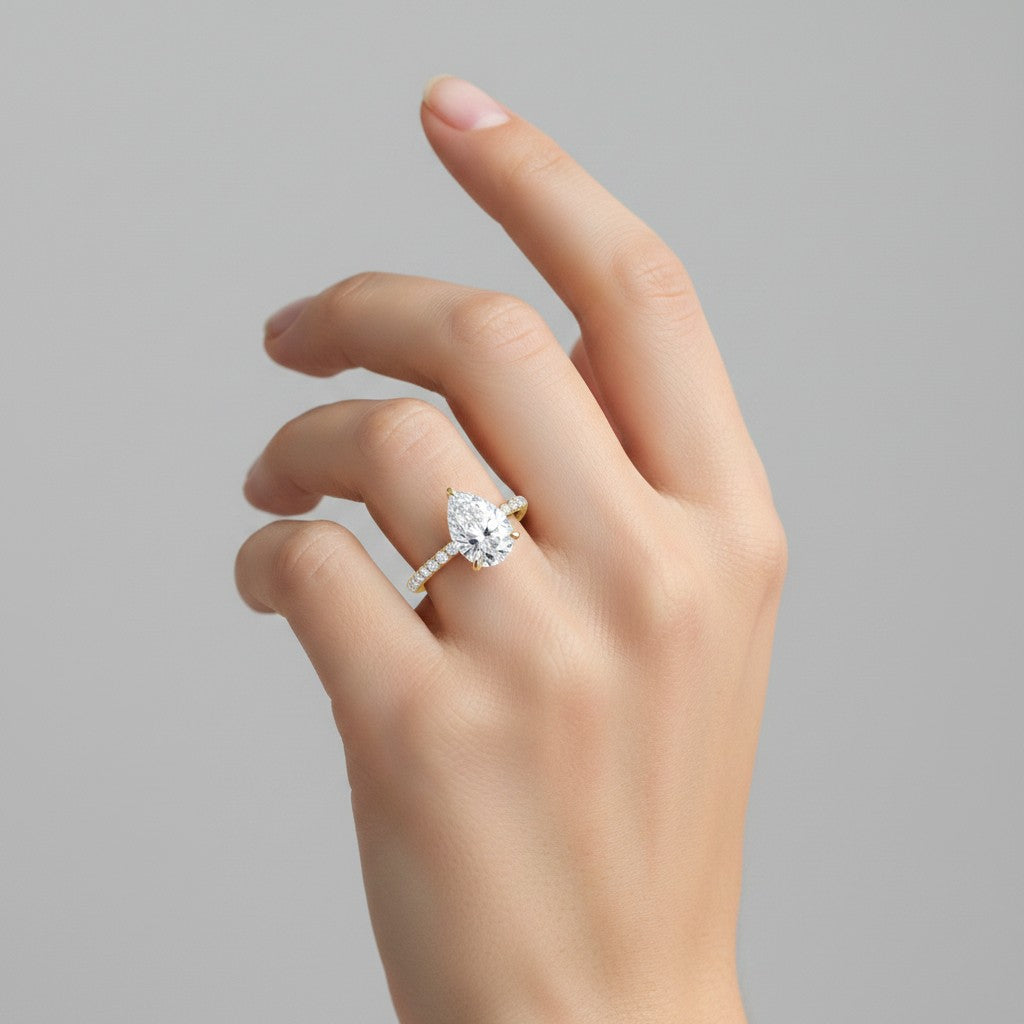 My Store 4 pear cut diamond engagement ring with a pavé band and hidden halo on a woman's finger in yellow gold