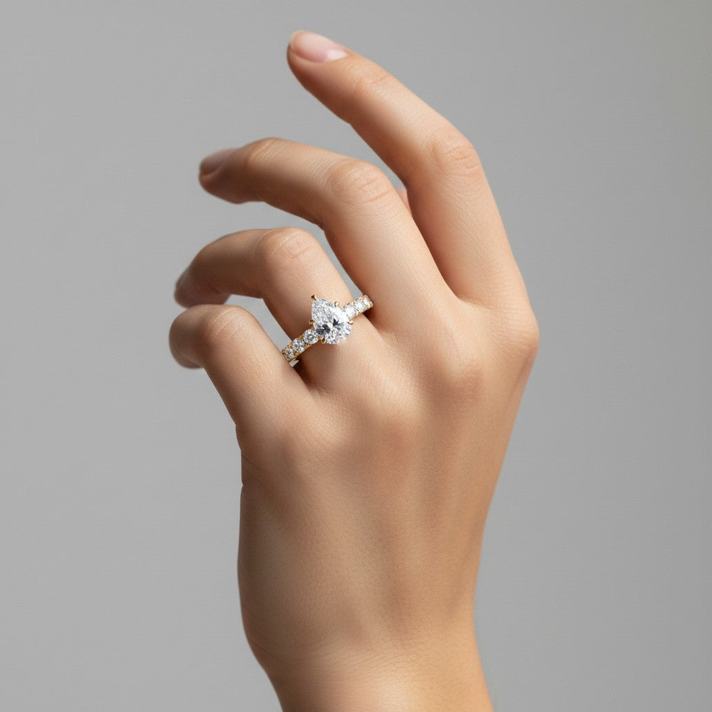 My Store 4 pear cut diamond engagement ring with shared-prong accent band on a hand in 18K yellow gold
