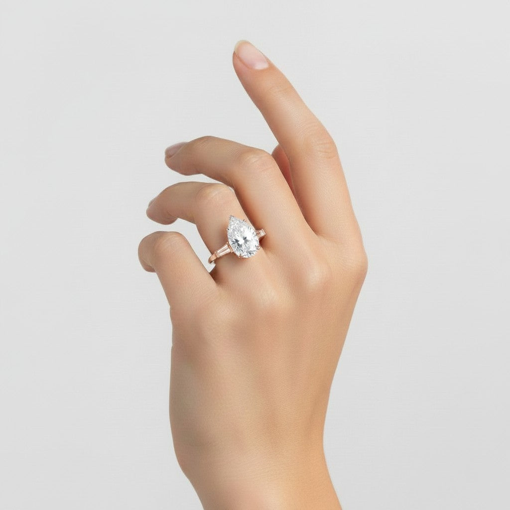 My Store 4 pear cut engagement ring with tapered baguette side diamonds on a woman's hand in solid gold