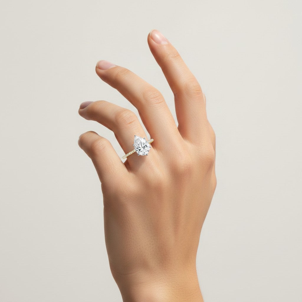 My Store 4 pear cut diamond engagement ring with a micro-pavé band on a hand, featuring a six-prong yellow gold setting.