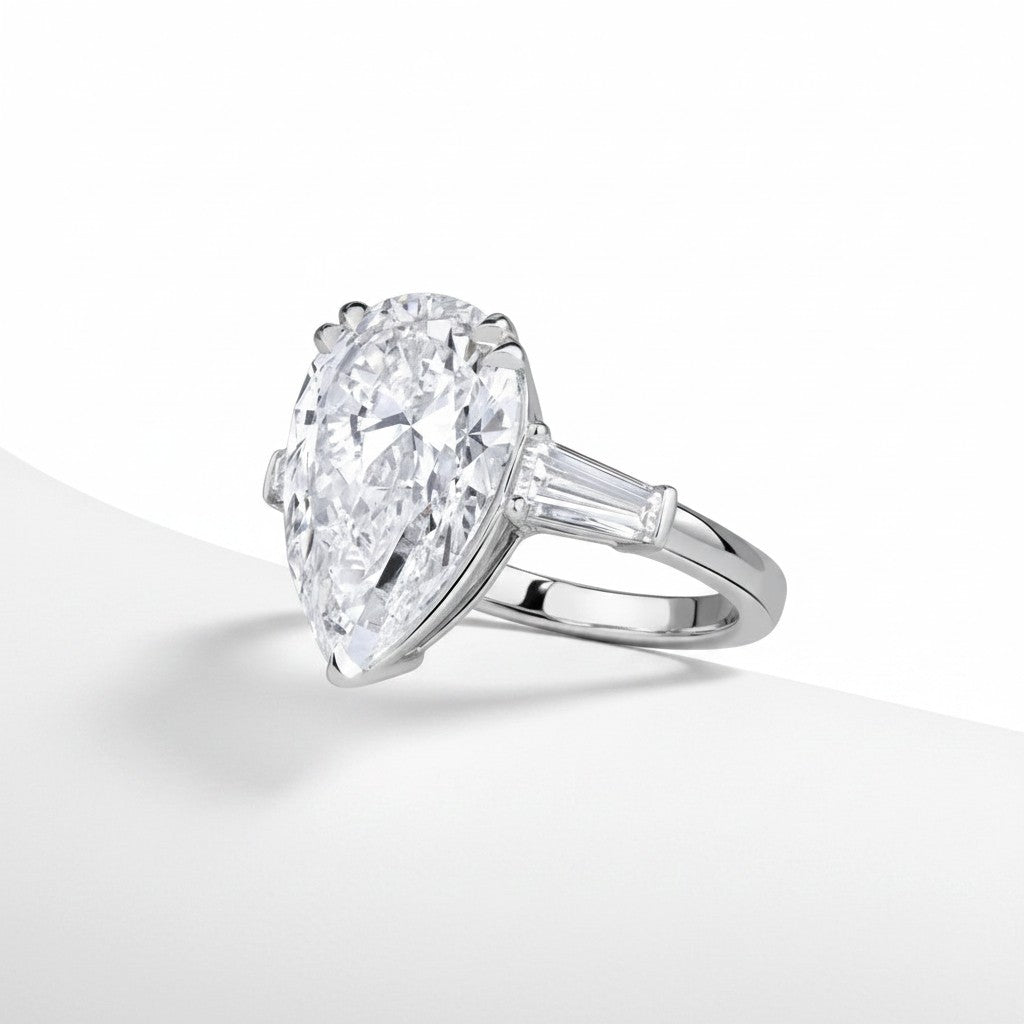 My Store 4 pear cut engagement ring with tapered baguette side diamonds in polished white gold on a white background.