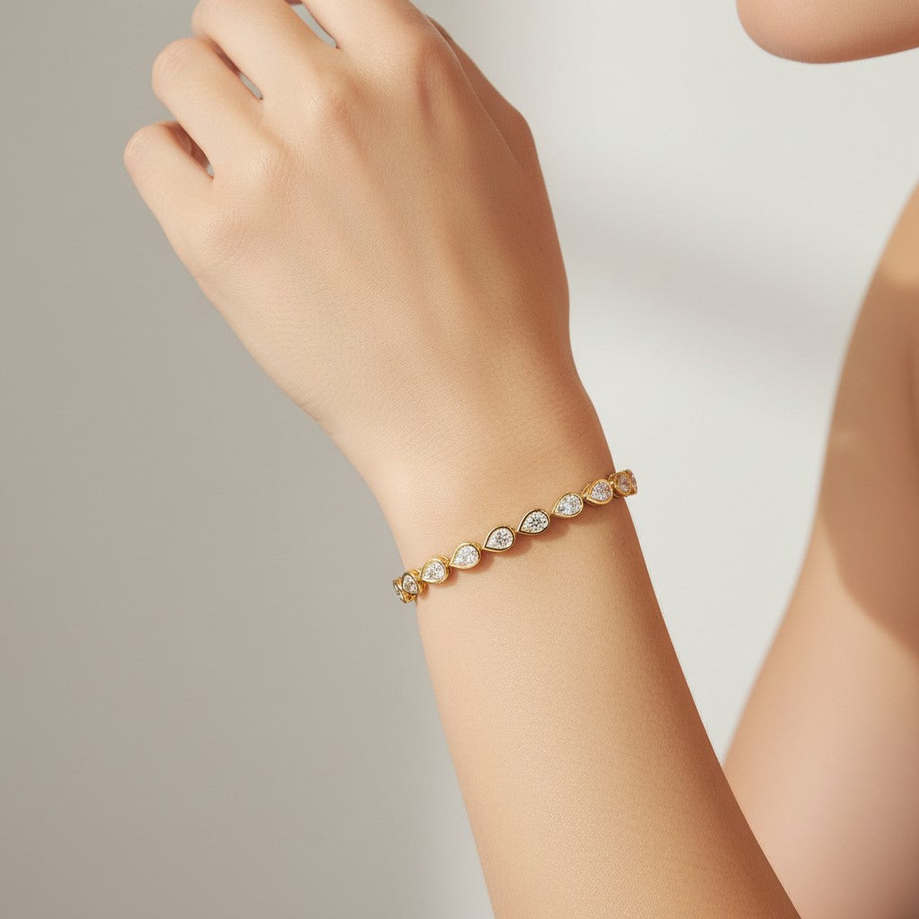 My Store 4 pear cut diamond tennis bracelet in yellow gold with smooth bezel settings worn on a woman's wrist.
