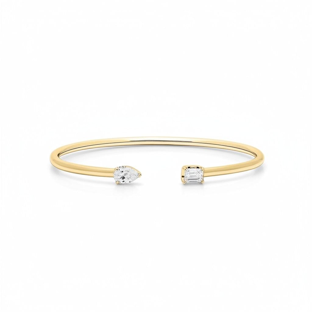 My Store 4 open cuff bracelet in yellow gold featuring an asymmetrical pear-cut and emerald-cut diamond solitaire.
