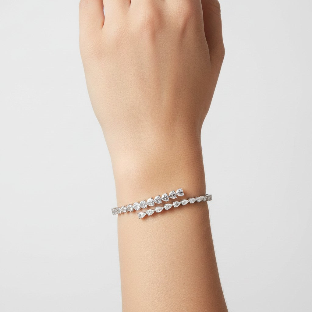 My Store 4 pear and heart diamond bypass open bangle bracelet in white gold worn on a wrist.