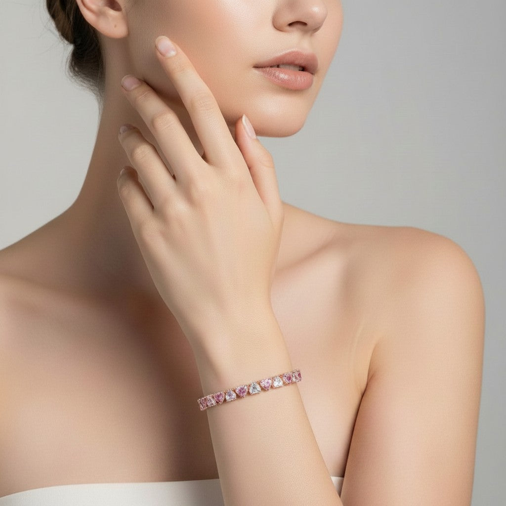 My Store 4 pink and white heart-cut diamond tennis bracelet worn on a woman's wrist in a gold setting.