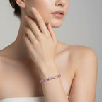 My Store 4 pink and white heart-cut diamond tennis bracelet worn on a woman's wrist in a gold setting.