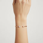 My Store 4 open cuff bracelet in rose gold featuring a pear-cut and emerald-cut diamond on a woman's wrist.