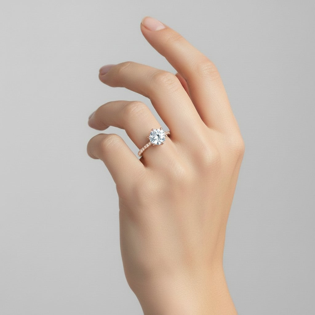 My Store 4 round cut engagement ring with a hidden pavé halo and six-prong setting on a hand in 18K yellow gold.