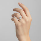 My Store 4 round cut engagement ring with a hidden pavé halo and six-prong setting on a hand in 18K yellow gold.