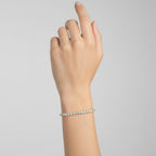 My Store 4 custom 4-prong round brilliant diamond tennis bracelet in yellow gold worn on a woman's wrist.