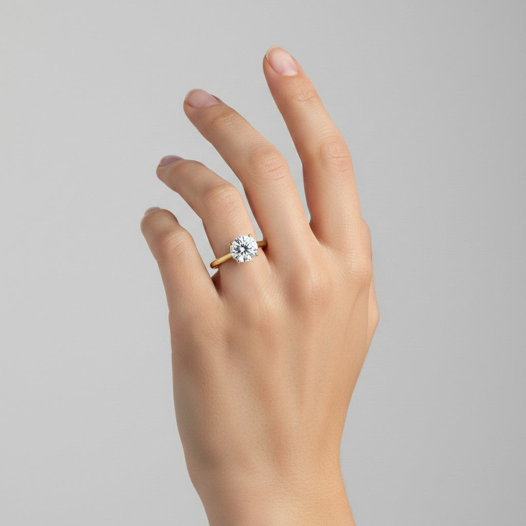 My Store 4 round cut solitaire engagement ring in yellow gold with a 4-prong setting worn on a woman's hand