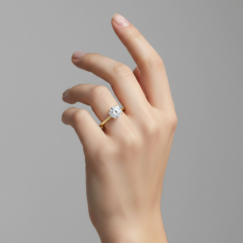 My Store 4 classic round cut solitaire engagement ring with a brilliant diamond on a slim yellow gold band on a hand