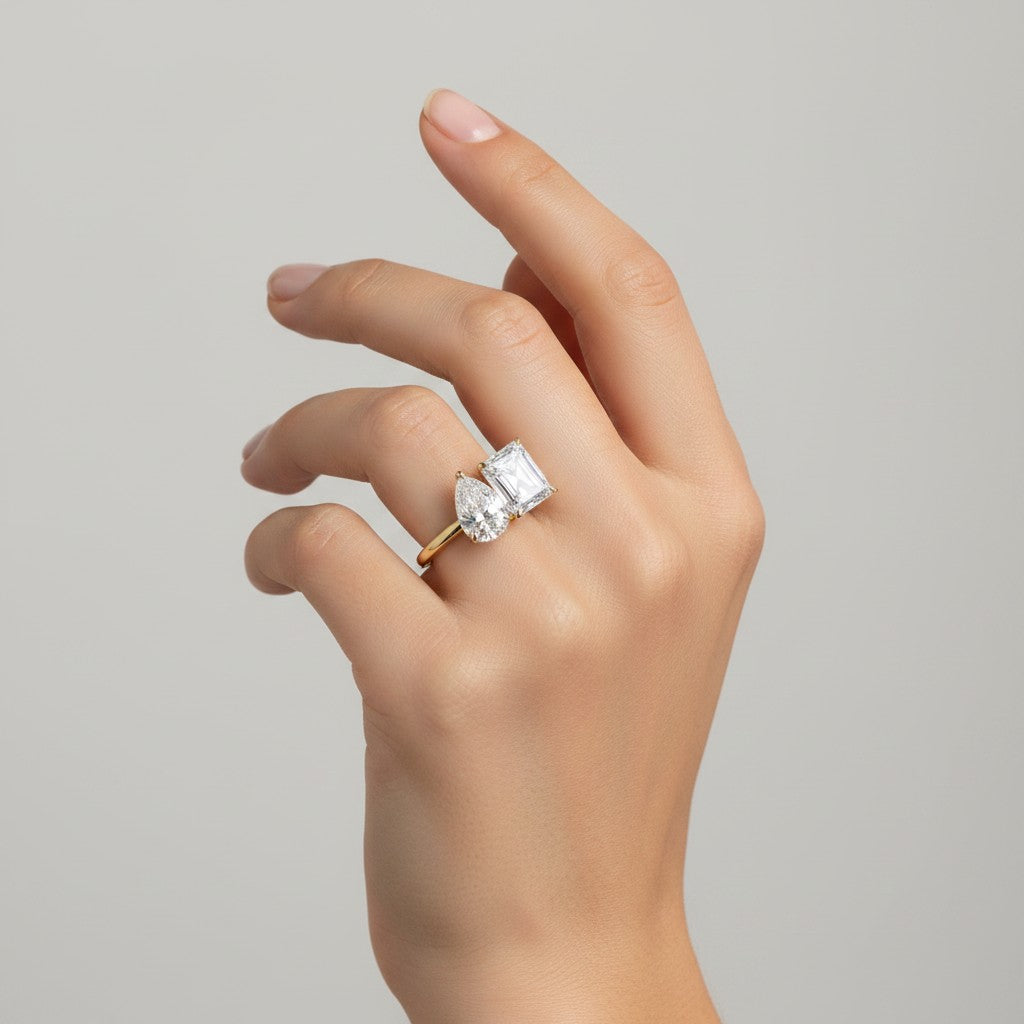 My Store 4 Toi et Moi ring featuring a pear and radiant cut diamond on a polished yellow gold band worn on a hand.