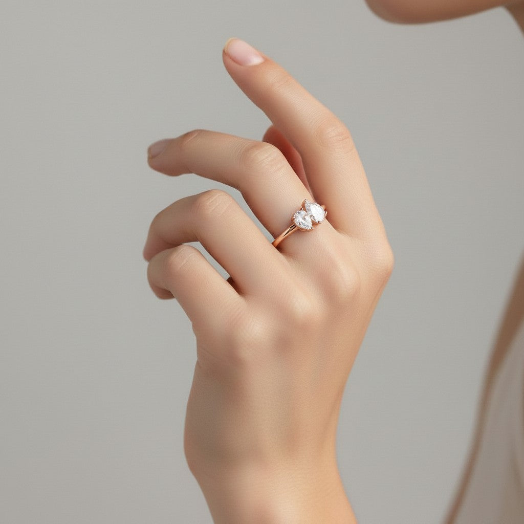 My Store 4 Toi et Moi engagement ring featuring two pear-cut diamonds on a polished yellow gold band worn on a finger.