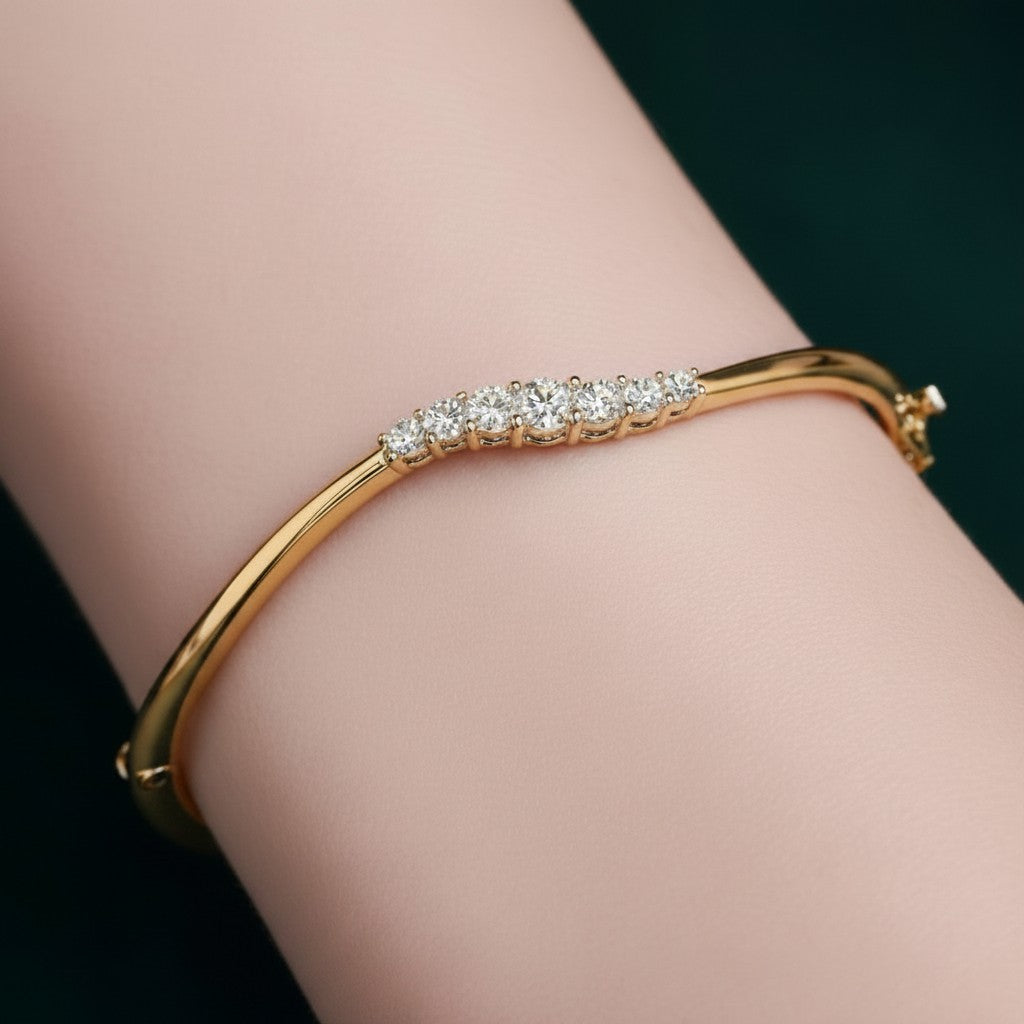 My Store 4 wave-contoured yellow gold bangle featuring a graduated row of round brilliant diamonds on a wrist.