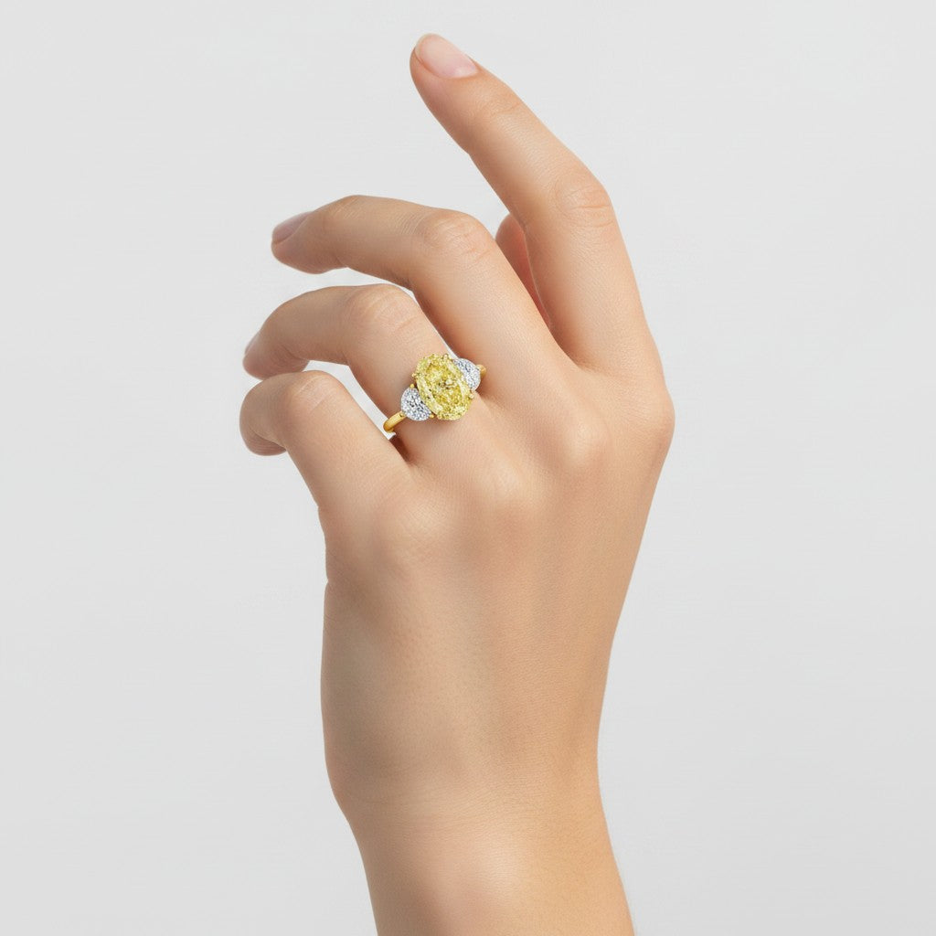 My Store 4 18K solid gold trilogy ring featuring a fancy yellow oval lab-grown diamond on a woman's hand.