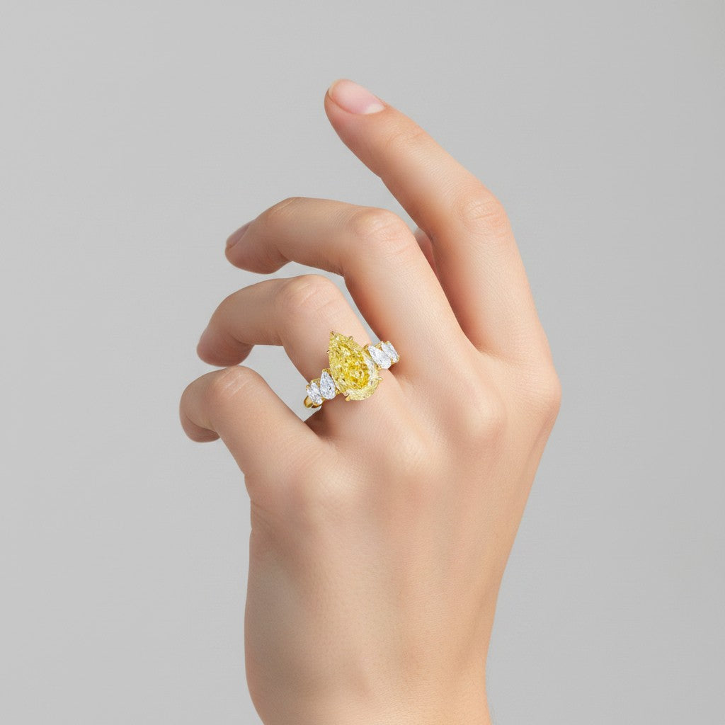 My Store 4 18K solid gold ring featuring a pear-cut fancy yellow lab-grown diamond with side stones on a hand.