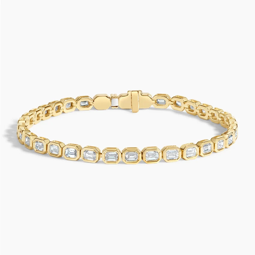 Gold tennis bracelet with emerald-cut diamonds in bezel settings on white background